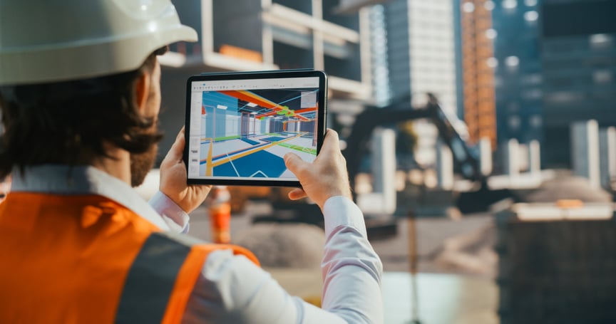 “Construction engineer using a tablet with 3D building design software to visualize project plans at a modern construction site